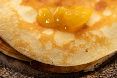 Üstünde kayısı reçeli ve süslü metal bir tabakta servis edilen ince krep yığını. Geleneksel ev yapımı tatlı meyveli kahvaltı..