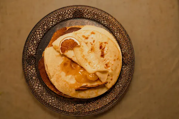 Kurutulmuş portakal dilimi ve altın kayısı reçeli ile servis edilen krep yığını. Zarif kahvaltı mı yoksa kırsal tonda tatlı fikri mi?.