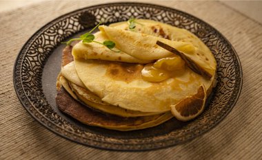 Kurutulmuş portakal dilimi ve altın kayısı reçeli ile servis edilen kırsal krep yığını. Kahvaltıda, kahvaltıda, kahvaltıda ya da atıştırmalıkta sıcak ev yapımı tatlı..