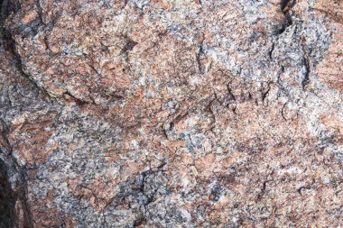 Pembe, gri ve beyaz mineral desenli granit taş yüzeyinin detaylı bir yakın çekimi. Tasarım, yapı, jeoloji ve doku kavramları için ideal doğal arkaplan.