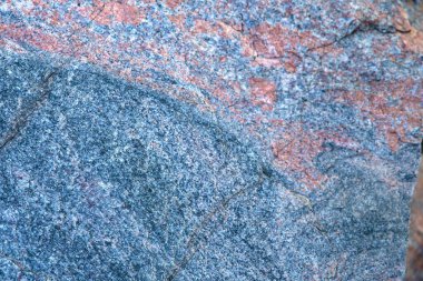 Pembe, gri ve beyaz mineral desenli granit taş yüzeyinin detaylı bir yakın çekimi. Tasarım, yapı, jeoloji ve doku kavramları için ideal doğal arkaplan.