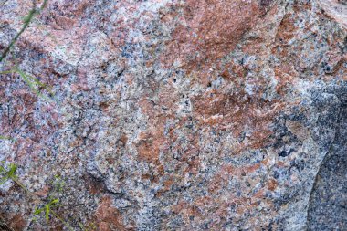 Pembe, gri ve beyaz mineral desenli granit taş yüzeyinin detaylı bir yakın çekimi. Tasarım, yapı, jeoloji ve doku kavramları için ideal doğal arkaplan.