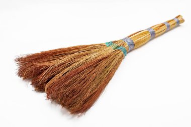 Ahşap saplı saman süpürgesi ve arka planda izole edilmiş renkli iplikler, ev ve bahçe için geleneksel temizlik aracı.