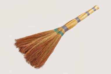 Ahşap saplı saman süpürgesi ve arka planda izole edilmiş renkli iplikler, ev ve bahçe için geleneksel temizlik aracı.