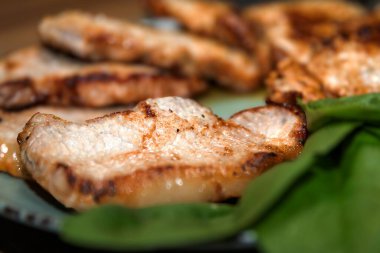 Lezzetli ızgara domuz bifteği ve tabakta taze yeşil yapraklarla servis edilen kıtır kıtır altın. Lezzetli ev yemeği..