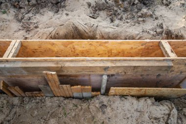 Kum ve toprakla çevrili bir inşaat sahasının beton temeli için ahşap kaplama..