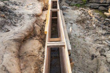 İnşaat sahasındaki bir hendekte uzun ahşap işçiliği. İnşaat temeli için beton dökülmeye hazır..