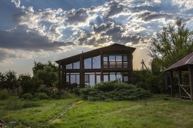 Günbatımında Büyük Pencereli Modern Ahşap Ev Yeşil Bahçede Bulutlu Gökyüzü