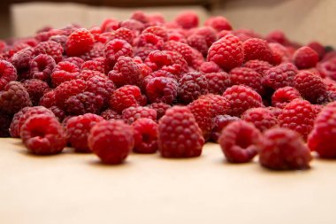 Kraft kağıdına serpilmiş taze kırmızı ahududular. Sağlıklı organik gıda kavramı, yaz hasadı ve çevre dostu ambalaj.