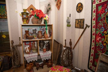 Ahşap raflar, 10 Temmuz 2025 'te Poltava' da düzenlenen kültür mirası sergisinde el yapımı çömlek, dekoratif semaver, dönen tekerlekler, tekstil ve kil heykelcikleri sergiliyor..