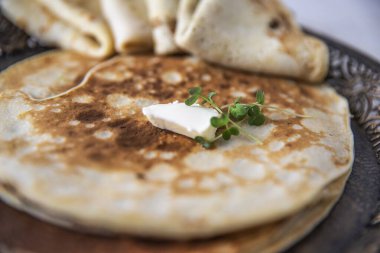 Krem peynirli katlanmış krep ve süslü bir tabakta mikro yeşiller..