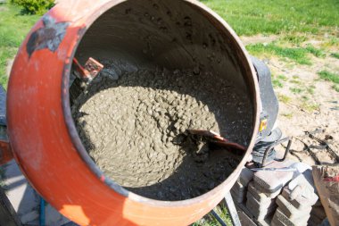 Turuncu taşınabilir mikserle çalkalanan ıslak beton yakın plan.
