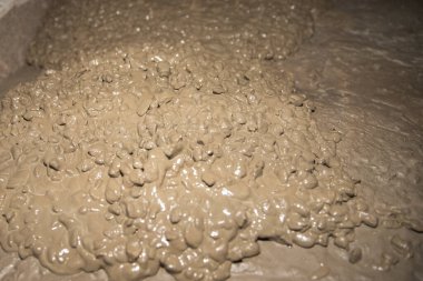 Islak betonun yakın plan birleşimi, kaba dokusunu ve kremsi tutarlılığını gözler önüne seriyor, inşaat ve endüstriyel arka planlar için ideal..