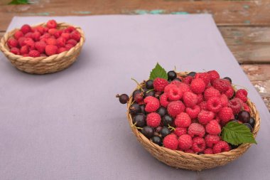 Taze ahududu ve siyah frenk üzümlü sepetler beyaz ve eflatun arkaplanlı, ipli. Yaz meyveleri, sağlıklı organik gıda ve vitaminler..