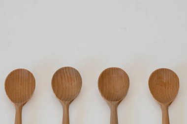 Temiz beyaz arka planda izole edilmiş dört ahşap kaşığın üst görüntüsü. Aşçılık ve yemek hazırlama için minimalist mutfak gereçleri kavramı.
