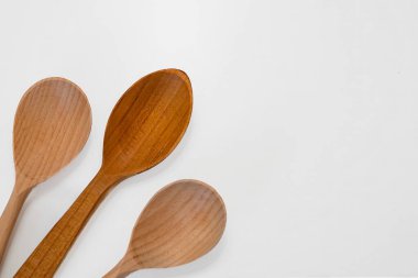 Beyaz arka planda üç tahta mutfak kaşığı. Doğal yaşam tarzı, ev yemekleri ve çevre dostu mutfak aletleri için minimalist mutfak aletleri konsepti.
