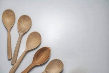 Beyaz arka plana dizilmiş beş tahta kaşık. Yemek pişirmek, hizmet etmek ve çevre dostu yaşam tarzı için kırsal doğal mutfak aletleri..