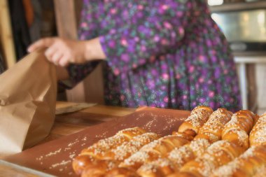 Pastanedeki kağıt torbaya susamlı taze ekmek ruloları dolduran ellerinizi kapatın.