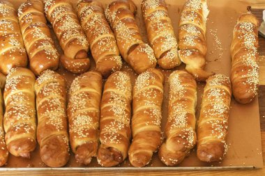 Sokak yemekhaneleri veya hızlı atıştırmalık seçenekler için ideal susam tohumlu altın fırınlanmış sosisli börekler.