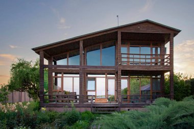 Yeşil bahçedeki panoramik pencereli çağdaş ahşap ev mimarlık ve emlak temaları için mükemmel.