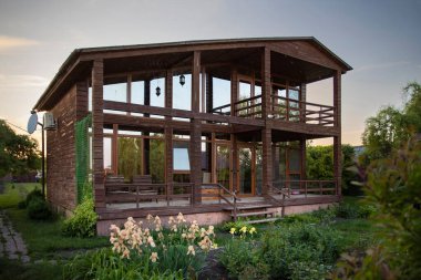 Yeşil bitkiler ve çimlerle çevrili büyük pencereli ahşap kır evi emlak ve yaşam tarzı kavramları için mükemmel.