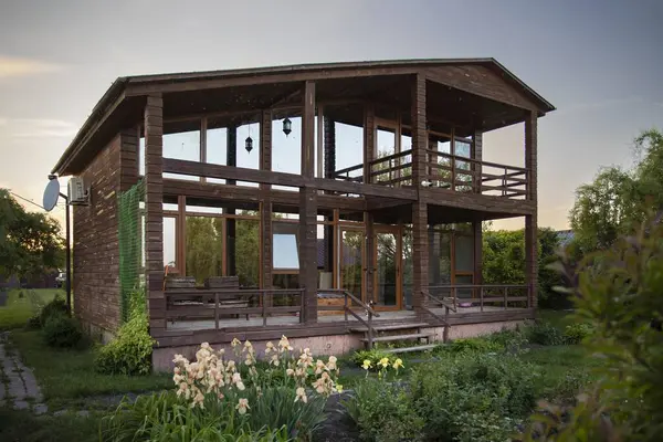 Yeşil bitkiler ve çimlerle çevrili büyük pencereli ahşap kır evi emlak ve yaşam tarzı kavramları için mükemmel.