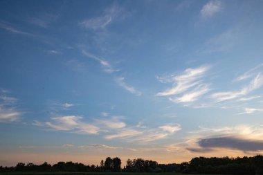 Güzel bir akşam gökyüzü batan güneşin sıcacık parıltısıyla aydınlanan narin beyaz bulutlarla tasarım ve doğa temaları için mükemmel doğal arka plan