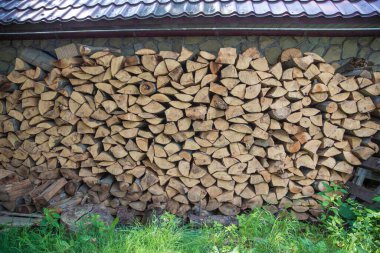 Odunları, taş kaplamalı bir evin duvarına düzgünce istiflemişler. Isıtma, şömine ya da açık hava pişirme için hazırlanmış odun yığını..