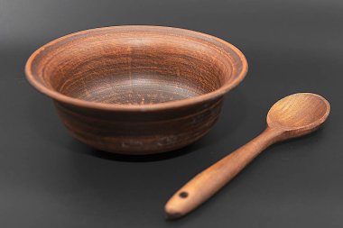 Siyah arka planda izole edilmiş tahta kaşıklı kil kase.