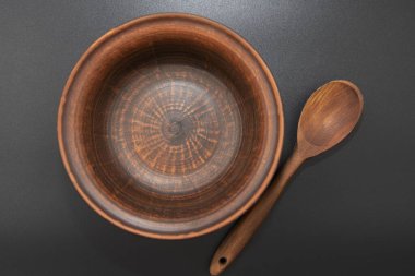 Siyah arka planda izole edilmiş tahta kaşıklı kil kase.