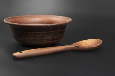 Siyah arka planda izole edilmiş tahta kaşıklı kil kase.