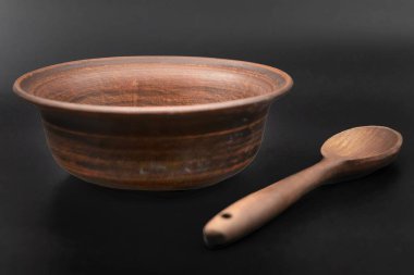 Siyah arka planda izole edilmiş tahta kaşıklı kil kase.