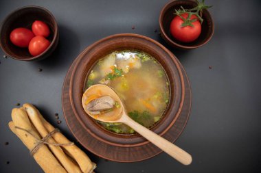 Sıcak çorba, ekmek çubuğu domates ve siyah arka planda izole edilmiş ahşap kaşık.