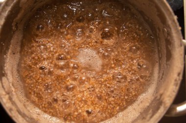 Yüzeyinde kabarcıklar olan metal bir tencerede lapa kaynıyor. Yemek pişirme, ev yapımı yemek, sağlıklı beslenme ve doğal yaşam tarzı kavramı..