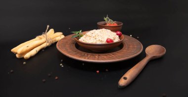 Yulaf lapası ve böğürtlenler koyu arka planda sunuluyor. Sağlıklı kahvaltı kavramı geleneksel organik gıda ve doğal yaşam tarzı.