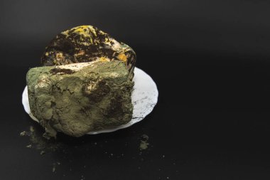 Bozulmuş ekmek tamamen yeşil siyah ve sarı mantarla kaplanmış. Koyu arka plan konsepti olan gıda atıkları, sağlıksız ürün ve zehirli kirlilik üzerine.