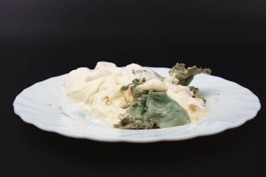 Beyaz tabakta servis edilen ekşi kremanın kapağı. Eskimiş yiyecek ve yiyecek bozulması kavramı üzerine izole edilmiş.