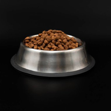 Paslanmaz çelik kasede kurutulmuş evcil hayvan yiyeceği siyah arka plan kavramına izole edilmiş kedi maması hayvan bakımı ve evcil hayvan beslenmesi.