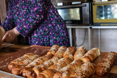 Pişirme tepsisinde susamlı dürüm ve fırın ve geleneksel yemek pişirme konseptinde ev yapımı hamur işi ve insan eli.