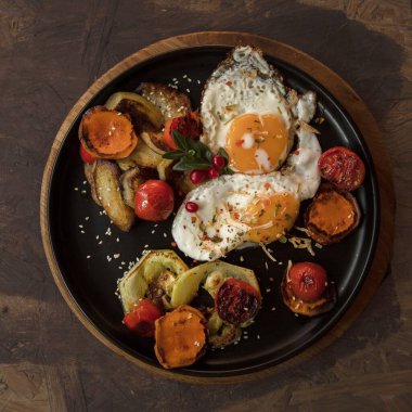 Siyah tabakta taze domatesli yumurta ve sebze. Sağlıklı kahvaltı konsepti.