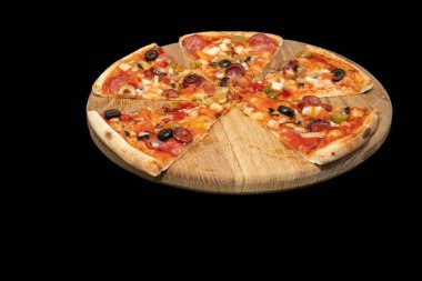 Siyah arka planda tahtadan servis edilen sosisli, sebzeli, peynirli ve zeytinli pizza. İtalyan yemeği, fast food, akşam yemeği, restoran menüsü ve teslimat kavramı.