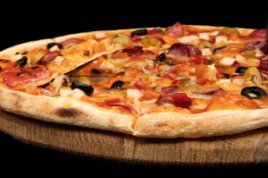 Siyah arka planda tahtadan servis edilen sosisli, sebzeli, peynirli ve zeytinli pizza. İtalyan yemeği, fast food, akşam yemeği, restoran menüsü ve teslimat kavramı.