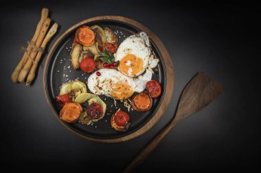 Kızarmış patates, havuç, kabak ve ekmek çubuklarıyla servis edilen domatesli omlet koyu arka planda sağlıklı kahvaltı.