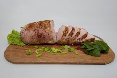 Baharatlı domuz filetosu, ahşap kesim tahtasına yeşil soğan ve bitkilerle yakın plan. Yemek tarifleri ve restoran menüsü için mükemmel ev yapımı yemekler.