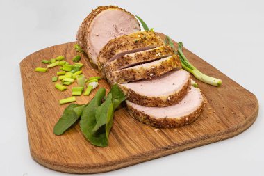 Baharatlı domuz filetosu, ahşap kesim tahtasına yeşil soğan ve bitkilerle yakın plan. Yemek tarifleri ve restoran menüsü için mükemmel ev yapımı yemekler.