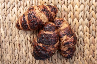 Üç tane taze kruvasan ve çikolata parçalı örülmüş saman arkaplan arkaplanlı lezzetli hamur işi kahvaltı tatlısı ve fırın reklamı için mükemmel.