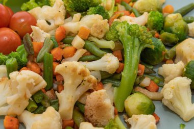 Brokoli karnabaharlı karışık sebzeleri kapayın. Brüksel lahanası, havuç ve yeşil fasulye tabakta servis edilir. Sağlıklı vejetaryen ve vejetaryen gıda kavramı.