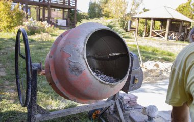 Açık hava inşaat alanında çakıl ve havan ile çimento karıştırıcısına yakın çekim. İnşaat malzemeleri, yenileme çalışmaları, inşaat mühendisliği ve somut hazırlık kavramı.