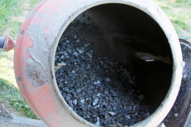 Açık hava inşaat alanında çakıl ve havan ile çimento karıştırıcısına yakın çekim. İnşaat malzemeleri, yenileme çalışmaları, inşaat mühendisliği ve somut hazırlık kavramı.