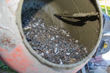 Açık hava inşaat alanında çakıl ve havan ile çimento karıştırıcısına yakın çekim. İnşaat malzemeleri, yenileme çalışmaları, inşaat mühendisliği ve somut hazırlık kavramı.